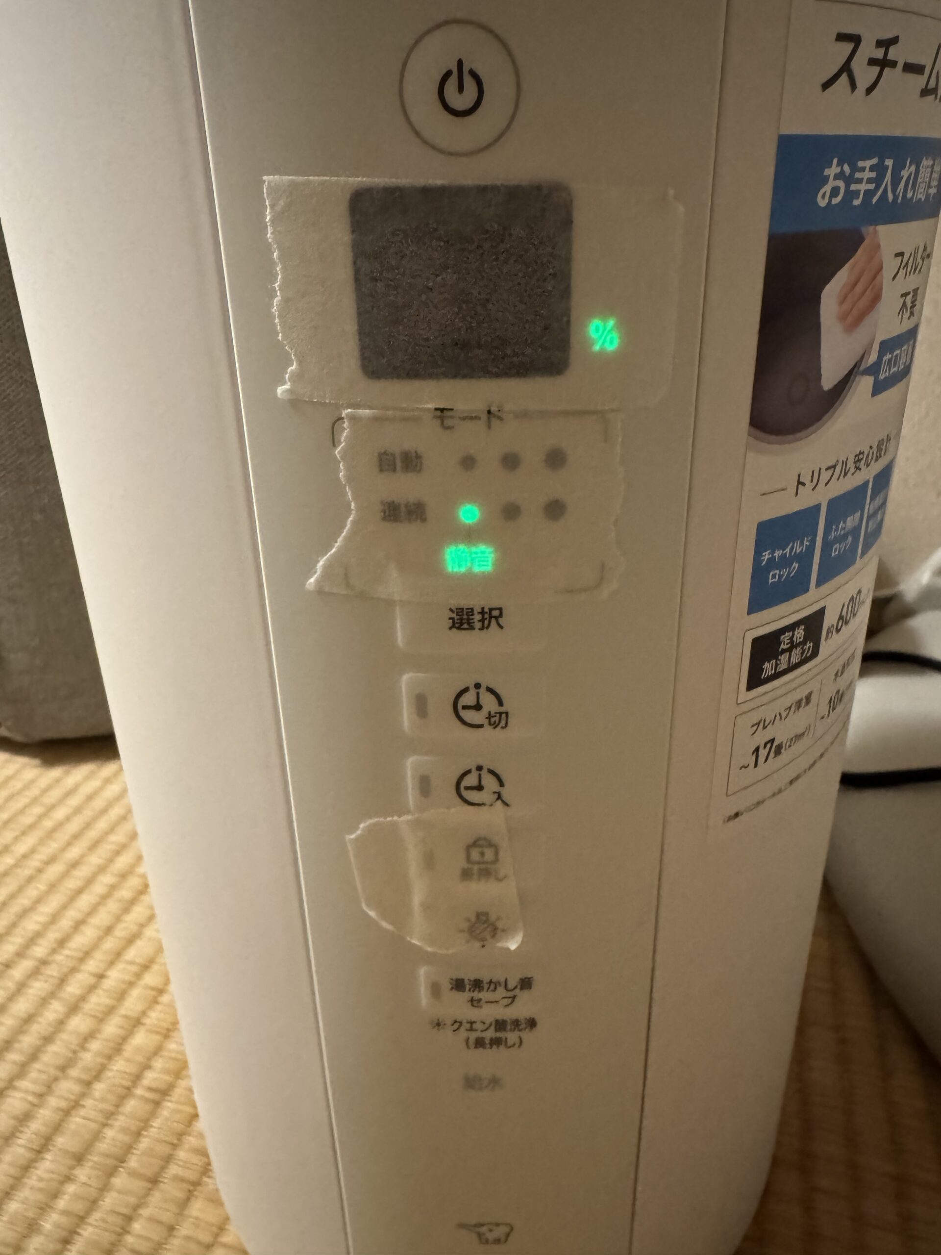 象印スチーム式加湿器の湿度表示部分にマスキングテープを貼って光量を弱めている様子。明るい部屋で撮影した、寝室での光対策の実例写真。