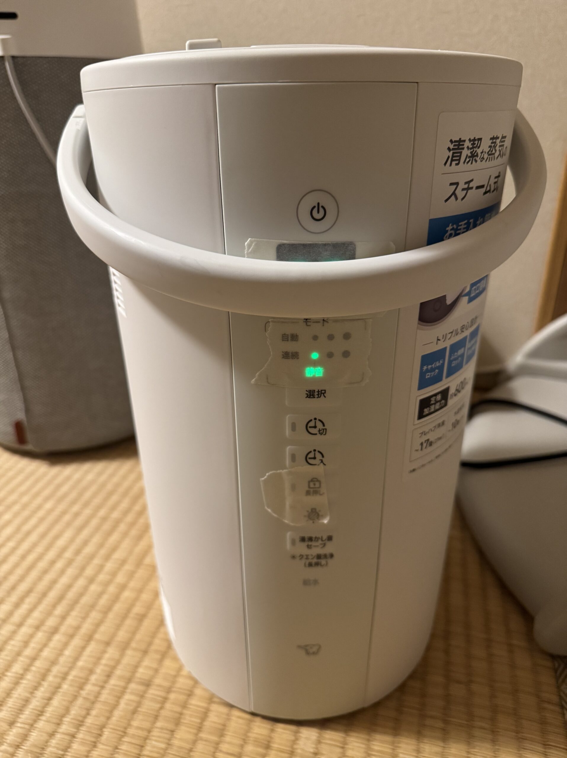 加湿器本体に湿度表示や各種ランプを覆うようにマスキングテープを貼り、光を和らげている様子。持ち手を前に倒して光をさらに遮っている配置。